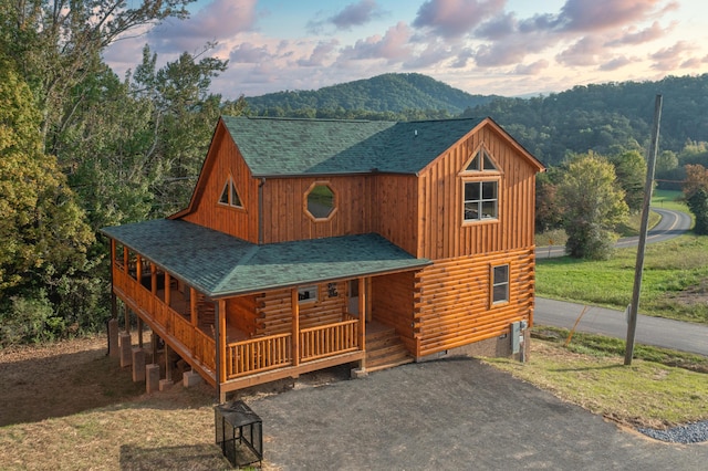 view of front facade featuring a lawn, a mountain view, and covered porch