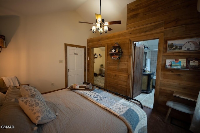 bedroom featuring high vaulted ceiling, ensuite bath, ceiling fan, and wood walls