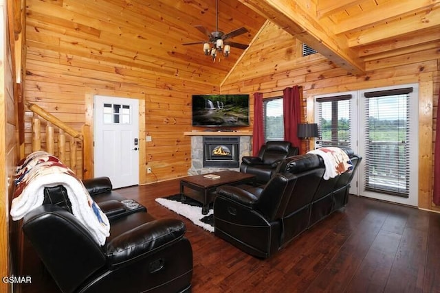 living area featuring a warm lit fireplace, wooden walls, lofted ceiling, wood-type flooring, and stairway