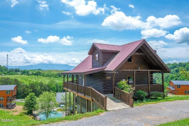 log-style house featuring metal roof, log exterior, a porch, and a mountain view