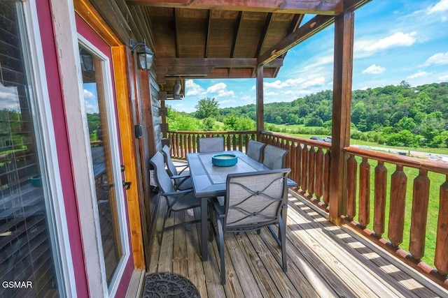 deck featuring outdoor dining area and a wooded view