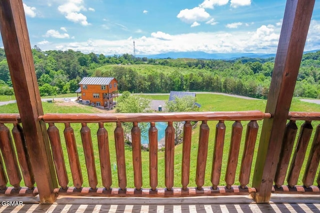 wooden deck with a lawn and a wooded view