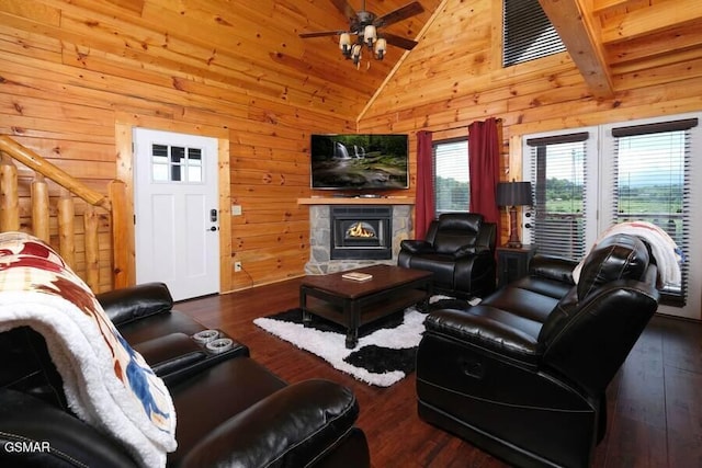 living area featuring a ceiling fan, a stone fireplace, wood-type flooring, and wooden walls