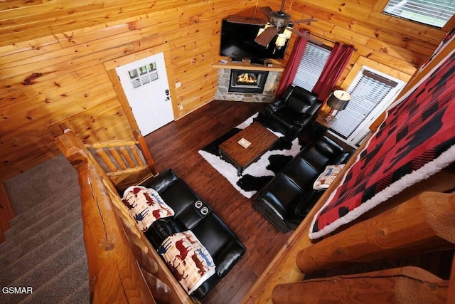 unfurnished living room featuring wood walls, a fireplace, wood finished floors, and a ceiling fan