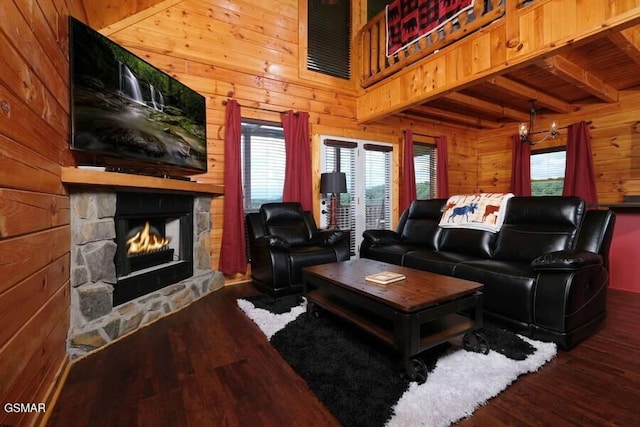 living room featuring a chandelier, a high ceiling, wood walls, a fireplace, and wood finished floors