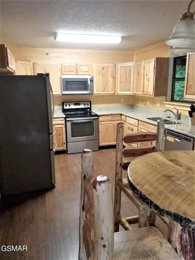 kitchen featuring sink, light brown cabinets, dark wood-type flooring, stainless steel appliances, and a textured ceiling