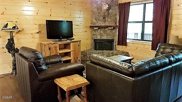 living room with wooden walls, a fireplace, and wood-type flooring