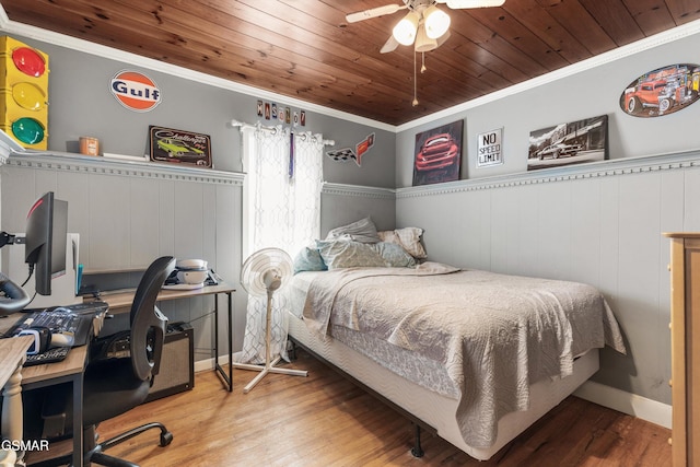 bedroom with a wainscoted wall, ornamental molding, wooden ceiling, wood finished floors, and a ceiling fan