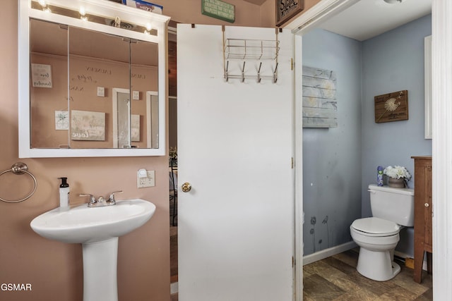 half bathroom with a sink, baseboards, and toilet