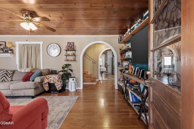 living area featuring hardwood / wood-style flooring, stairway, arched walkways, wooden ceiling, and ceiling fan