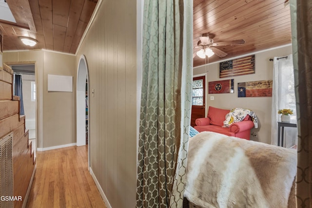 hallway featuring wooden ceiling, wood finished floors, crown molding, and baseboards