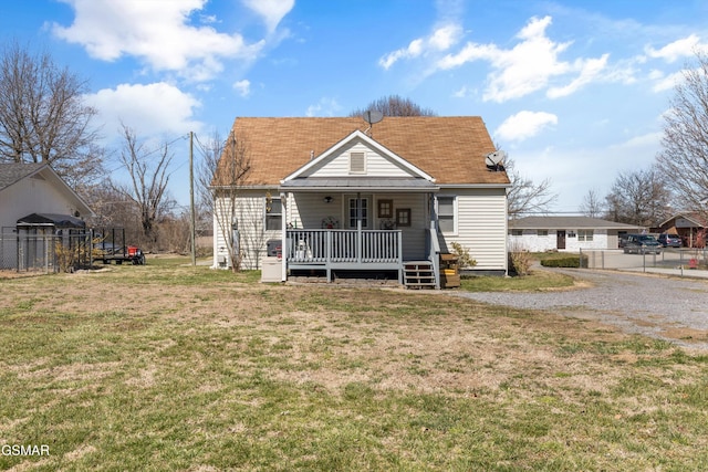 back of house with a porch, a yard, and fence