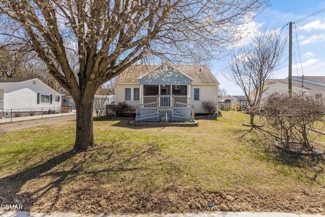 back of house featuring a porch, a lawn, and a shingled roof