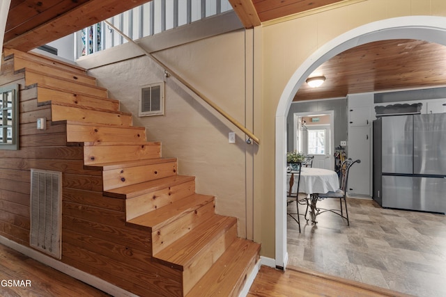 stairway featuring arched walkways, visible vents, and wood finished floors