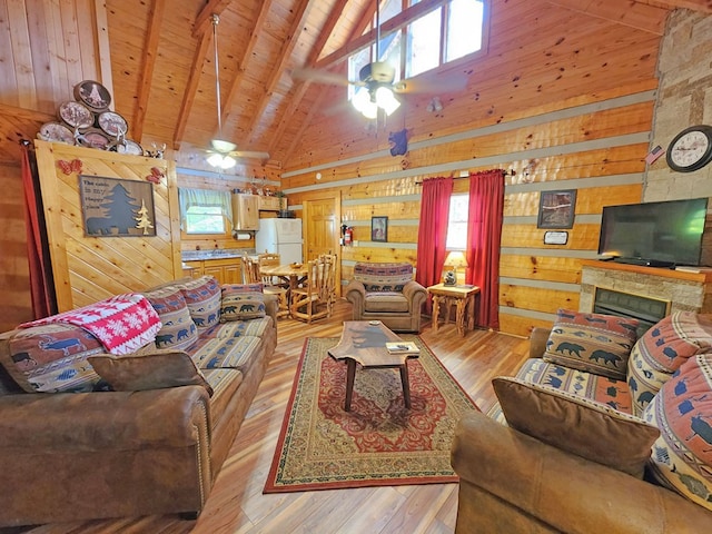 living room with beam ceiling, wood walls, ceiling fan, and light hardwood / wood-style floors