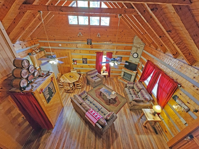 unfurnished living room with hardwood / wood-style floors, lofted ceiling with skylight, ceiling fan, and wooden walls