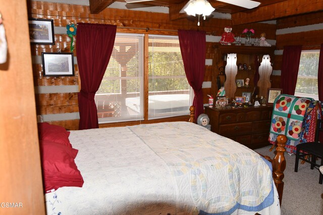 carpeted bedroom featuring ceiling fan and wood walls