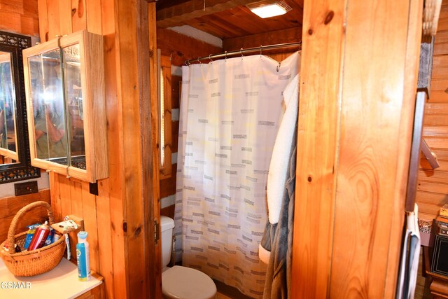 bathroom with wood walls, toilet, and wood ceiling