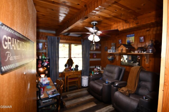 living room with beam ceiling, ceiling fan, wood ceiling, and wood walls