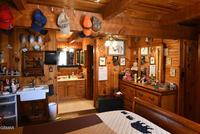 bedroom with beamed ceiling, wood walls, wooden ceiling, and sink