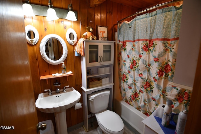 bathroom featuring toilet, wooden walls, and shower / tub combo with curtain