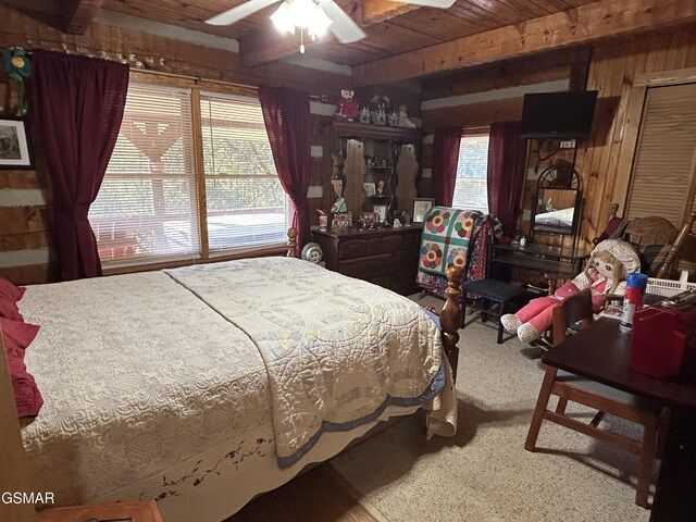 carpeted bedroom featuring wood walls, multiple windows, wooden ceiling, and ceiling fan