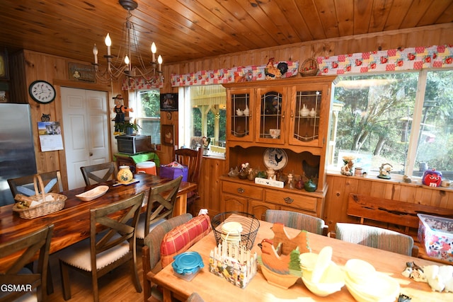 dining space featuring a chandelier, plenty of natural light, wooden ceiling, and wood walls