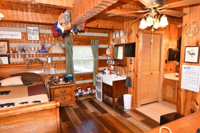 bedroom with sink, dark hardwood / wood-style floors, wood ceiling, and wood walls