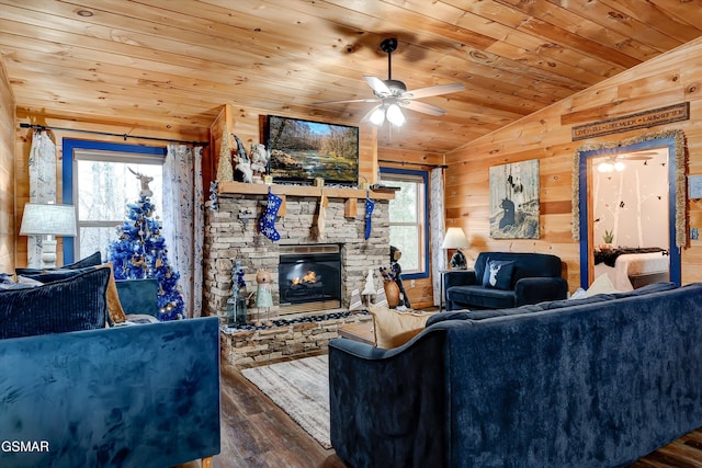 living room with dark wood-type flooring, wood walls, vaulted ceiling, a stone fireplace, and wooden ceiling