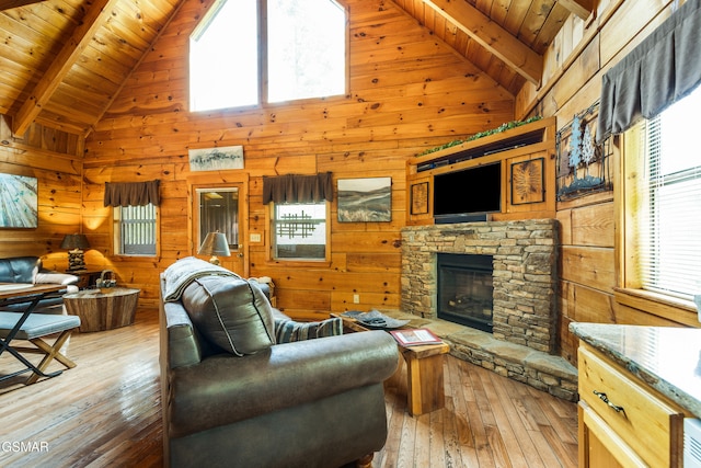 817 Eagle Cove Way, Gatlinburg, TN 37738 - living room featuring hardwood / wood-style flooring, wooden walls, high vaulted ceiling, a wood ceiling with exposed beams, and a stone fireplace