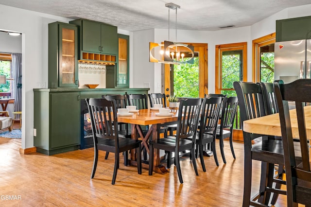 dining room with a chandelier, a textured ceiling, and light wood-type flooring