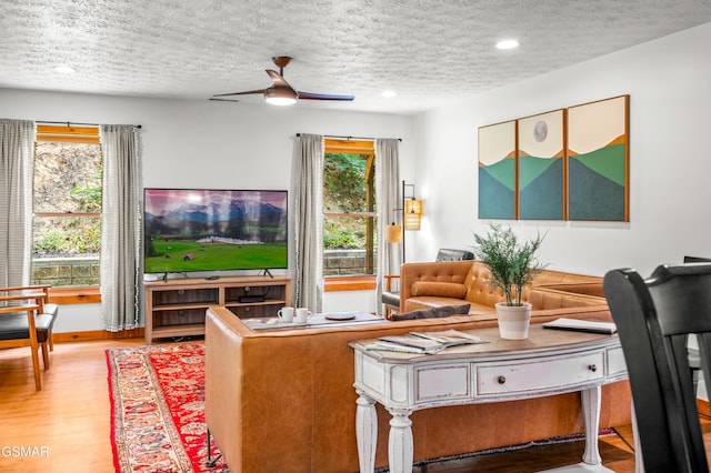 living room with a textured ceiling, light hardwood / wood-style floors, and ceiling fan