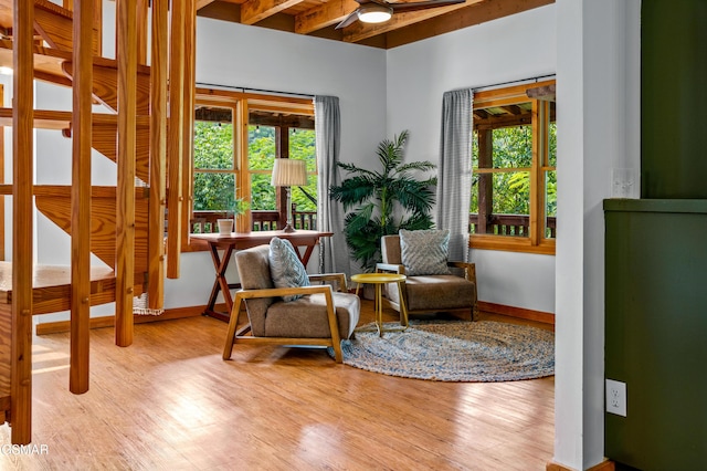 living area with beam ceiling, ceiling fan, and light hardwood / wood-style flooring