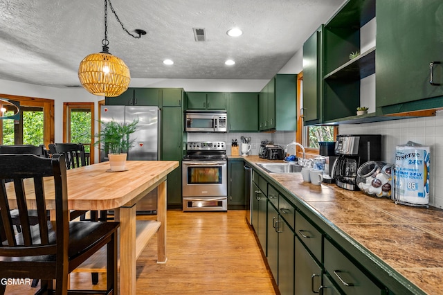 kitchen featuring backsplash, sink, green cabinetry, and appliances with stainless steel finishes