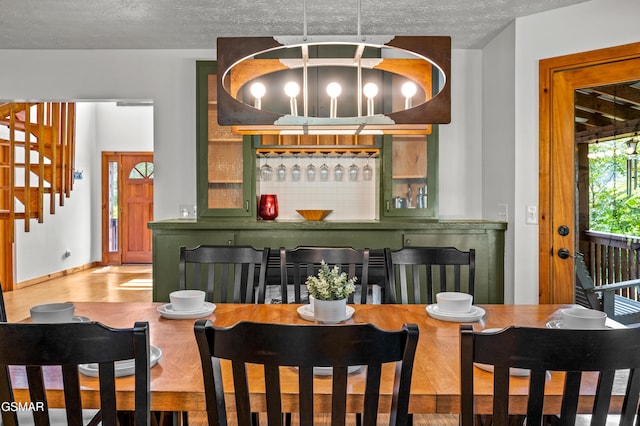 bar with a textured ceiling, decorative light fixtures, and green cabinetry