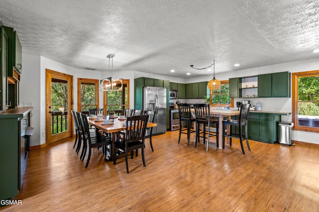 dining room featuring a notable chandelier, light hardwood / wood-style floors, and a textured ceiling