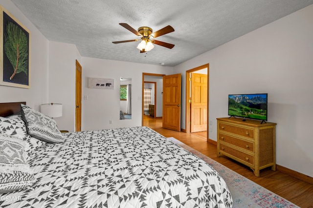 bedroom with ceiling fan, light wood-type flooring, and a textured ceiling