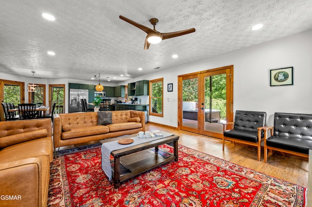 living room with french doors, a textured ceiling, hardwood / wood-style flooring, and ceiling fan