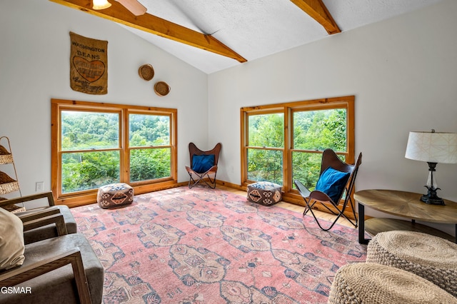 living room featuring vaulted ceiling with beams, a wealth of natural light, ceiling fan, and a textured ceiling