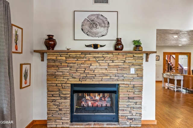 room details with hardwood / wood-style flooring and a stone fireplace