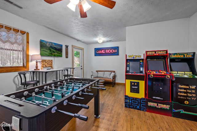 recreation room featuring hardwood / wood-style floors, ceiling fan, and a textured ceiling