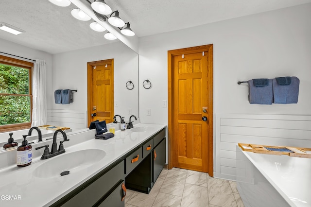 bathroom featuring a tub, vanity, and a textured ceiling