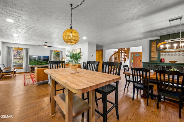 dining area with a textured ceiling, ceiling fan with notable chandelier, and hardwood / wood-style floors