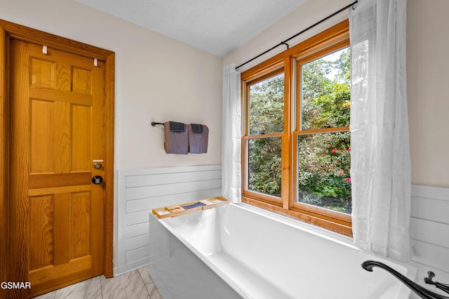 bathroom with a textured ceiling and a tub