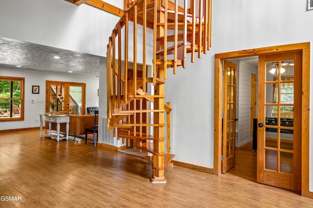 stairs with french doors and hardwood / wood-style flooring