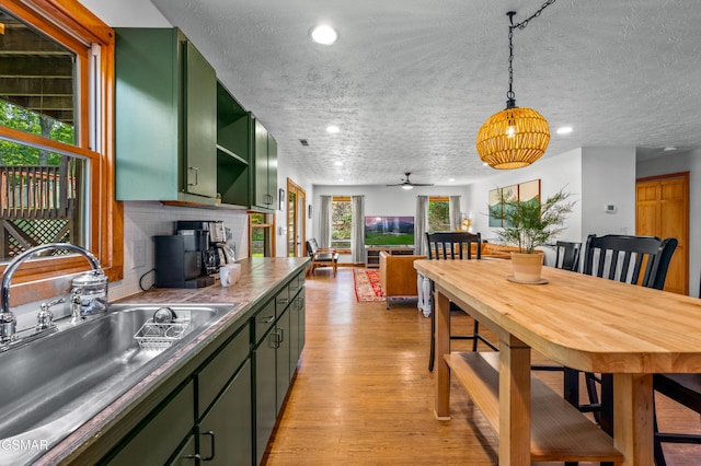 kitchen with decorative backsplash, ceiling fan, sink, a wood stove, and green cabinets