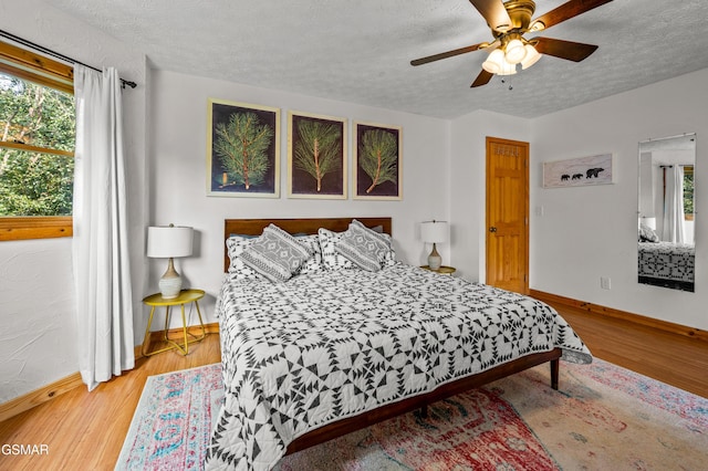 bedroom with ceiling fan, a textured ceiling, and light wood-type flooring