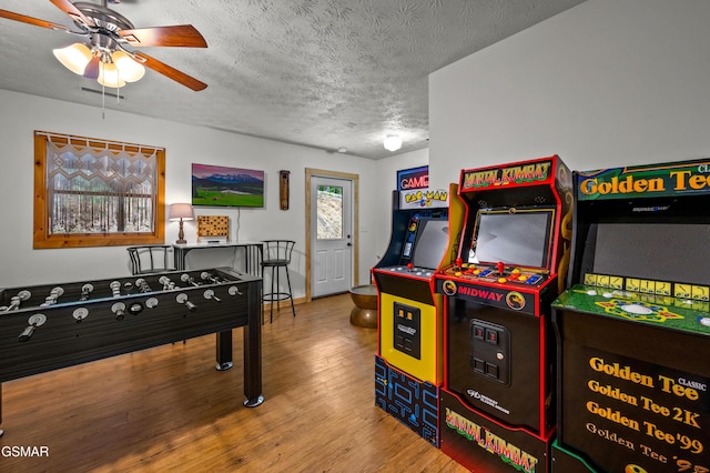 recreation room featuring a textured ceiling, hardwood / wood-style flooring, and ceiling fan