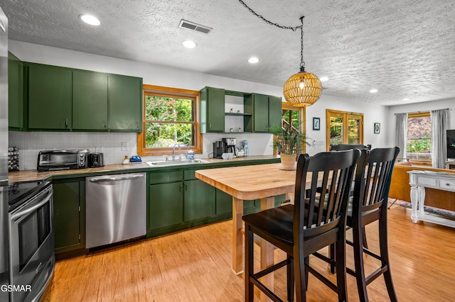 kitchen featuring stove, sink, light hardwood / wood-style flooring, dishwasher, and green cabinets