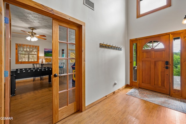 foyer entrance with ceiling fan, light wood-type flooring, and a textured ceiling